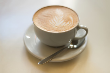 Cappuchino or latte coffe in a white cup on a light background