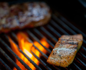hot dogs, steaks and salmon on a grill