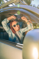 Naklejka premium Happy woman raising arms and having fun inside of car