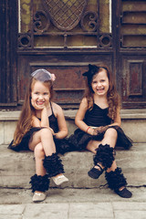 Two little ballerinas in black tutu sitting on staris