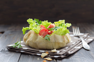 Salad in a bread bowl on a wooden table, selective focus