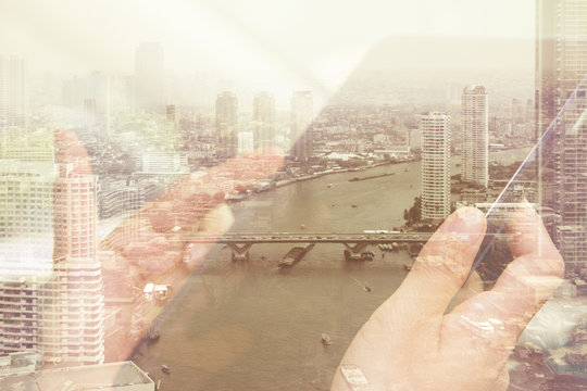 Using digital tablet double exposure and and cityscape background. Business  technology concept.