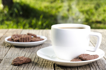 Cup of coffee with steam on a natural background