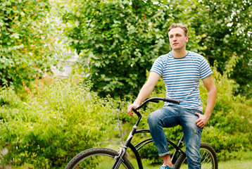 Naklejka premium A young man on a bicycle looks into the distance