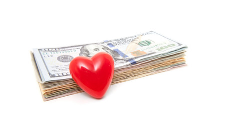 Red heart next to pile of dollar notes