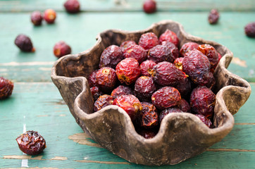 Dried rose hips in bowl on wooden background