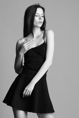 beautiful young model in elegant black dress posing in the studi