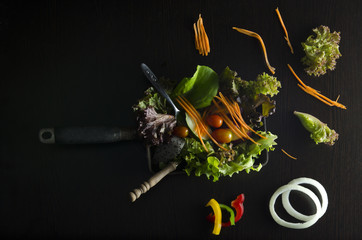 Vegetable salad preparation on black background