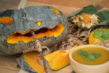 Halloween pumpkins and pumpkin soup on wood background.