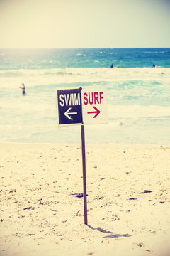 Retro toned swim and surf sign on the beach, California, USA.