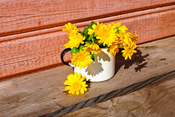 Yellow calendula on the unpainted wooden surface