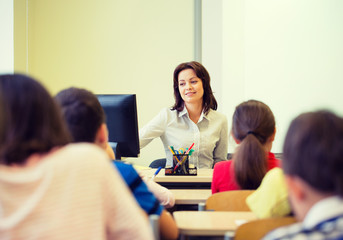group of school kids raising hands in classroom