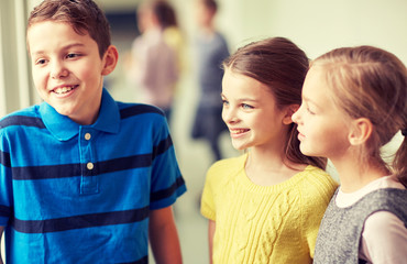 group of smiling school kids talking in corridor