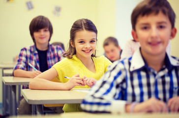 group of school kids with notebooks in classroom