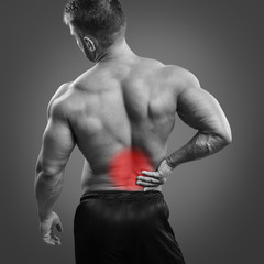 Muscular man with back pain over gray background. Concept with highlighted glowing red spot.