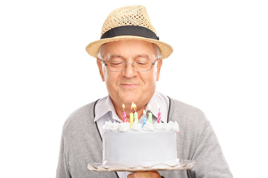 Senior Blowing Candles On A Birthday Cake