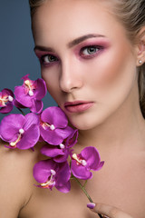 Portrait of a beautiful blonde woman holding orchid