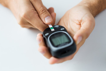close up of man checking blood sugar by glucometer