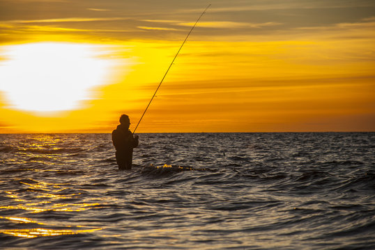 Angler fishing at the coast in an Autumn sunset