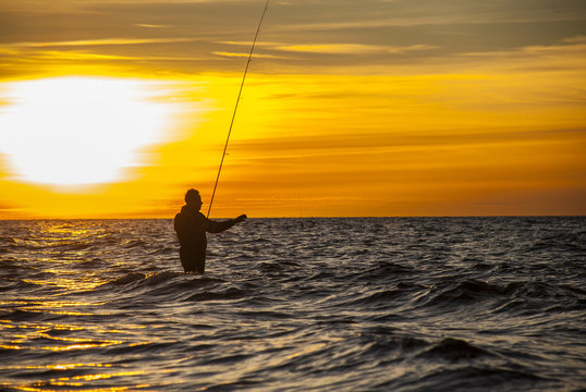 Angler fishing at the coast in an Autumn sunset