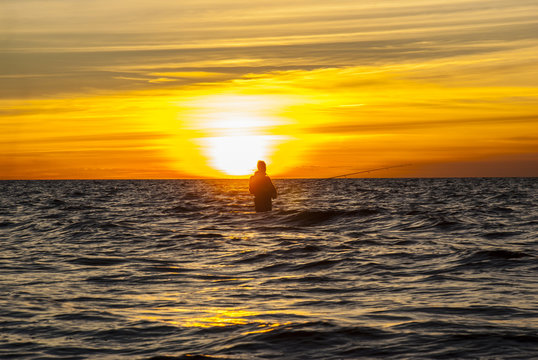 Angler fishing at the coast in an Autumn sunset
