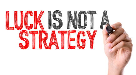 Hand with marker writing: Luck Is Not a Strategy