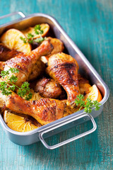Roasted chicken legs with oranges, selective focus