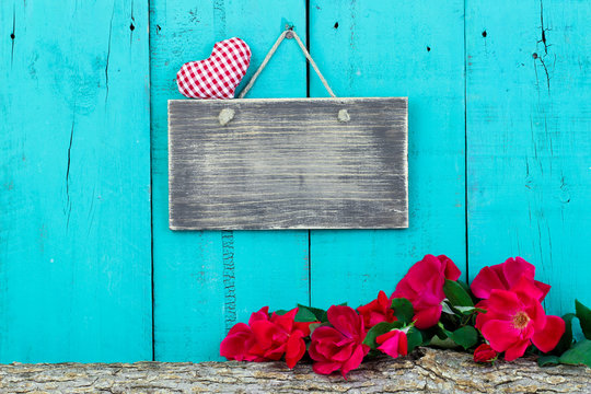 Blank sign with heart hanging hanging on fence by rose covered log