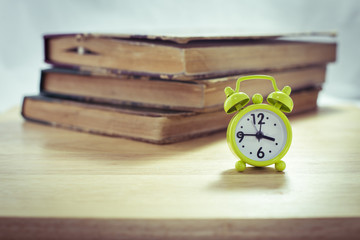 Vintage of green alarm clock and stack of books on a white backg