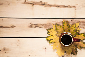 Autumn background. Cup of coffee on the table with leaves
