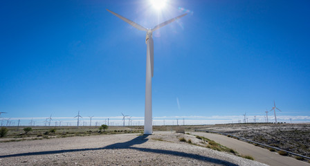 Fototapeta na wymiar Wind turbine against sun and windmill farm