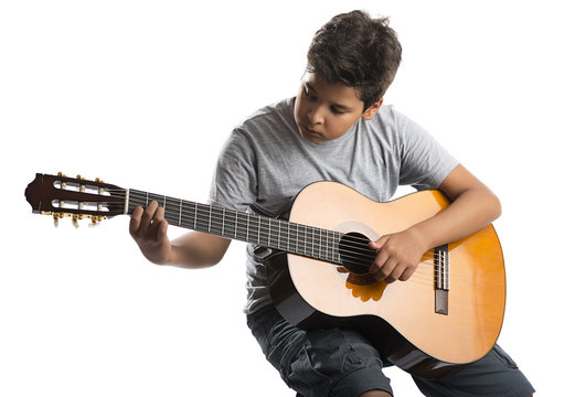 Child on chair playing classical guitar isolated on white background.