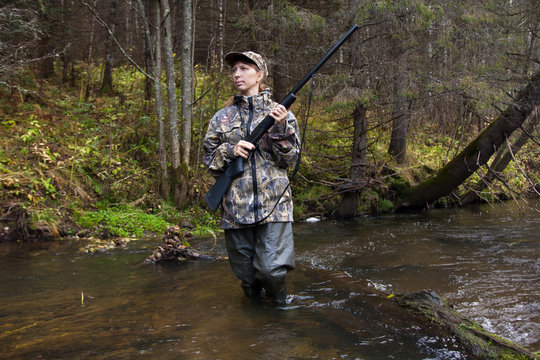 Woman hunter with gun on the river