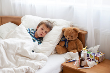 Sick child boy lying in bed with a fever, resting