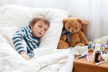 Fototapeta na wymiar Sick child boy lying in bed with a fever, resting