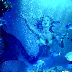 Mermaid dive underwater through coral .