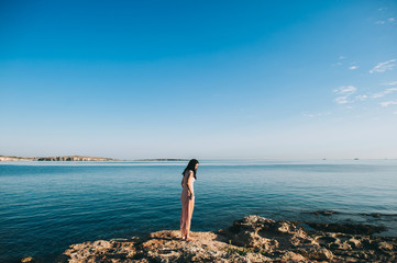 beautiful girl standing on rocky outcrops seaside