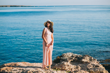 Fototapeta na wymiar beautiful girl standing on rocky outcrops seaside