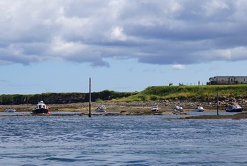 Fototapeta na wymiar Small boats at low tide in the harbor at the coastal town of Seahouses, Northumberland, England