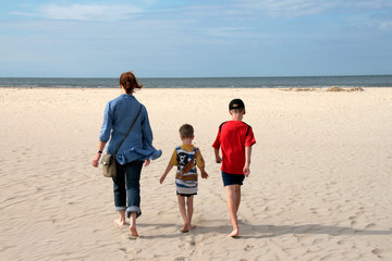 Familie mit Frau und zwei Kindern geht zum Strand
