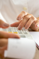 Front view of female accountant calculating with adding machine