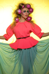 Cheerful girl with bright makeup and hair balls on a yellow background