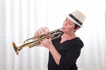 attractive woman with hat playing the trumpet