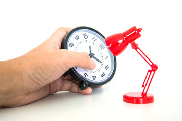 Hand holding alarm clock with red desk lamp
