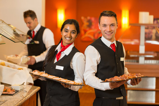 Waitress and waiters posing with food at buffet in a restaurant