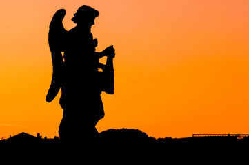 Sunset silhouette of an angel with the orange sky