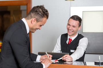 Receptionist at a hotel reception assisting guest