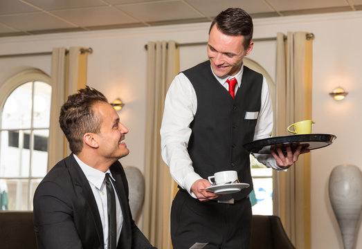 Concierge serving guest at hotel a cup of coffee