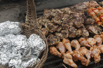 fried potato in foil and meat on barbecue grill