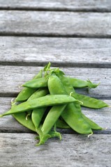 Freshly picked green peas in the pod on a wooden picnic table